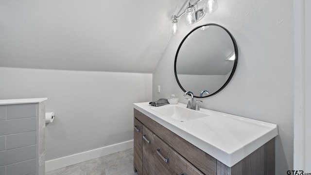 bathroom with vanity, baseboards, and vaulted ceiling