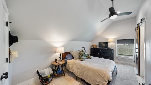 bedroom with baseboards, a barn door, a ceiling fan, and vaulted ceiling