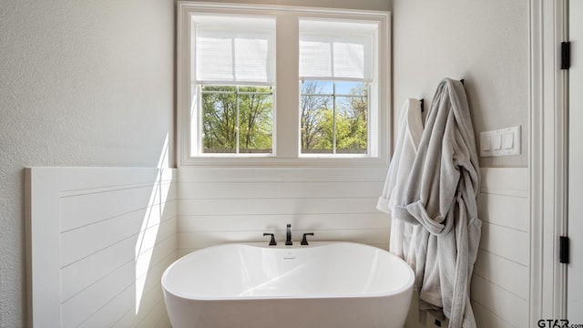 bathroom featuring a textured wall and a freestanding bath