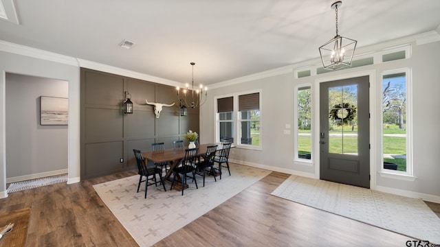 dining area featuring an inviting chandelier, ornamental molding, and wood finished floors
