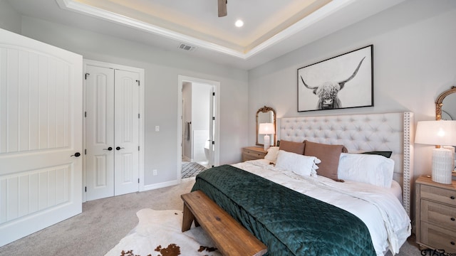 bedroom with carpet flooring, a raised ceiling, a ceiling fan, visible vents, and a closet