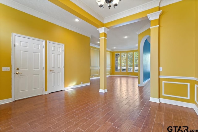 foyer with ornate columns, wood-type flooring, and ornamental molding