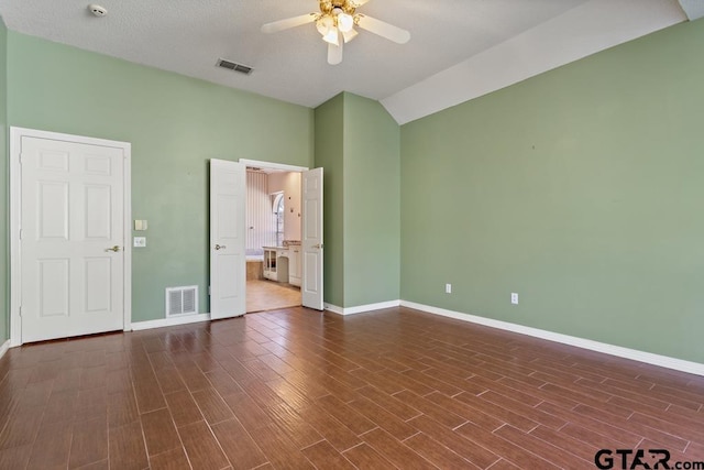 unfurnished bedroom featuring dark wood-type flooring, ensuite bath, vaulted ceiling, ceiling fan, and a textured ceiling