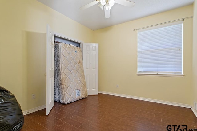 unfurnished bedroom featuring ceiling fan and dark wood-type flooring