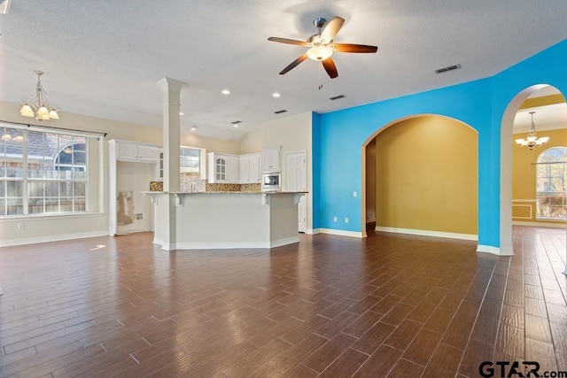 unfurnished living room featuring a textured ceiling, dark hardwood / wood-style floors, and ceiling fan with notable chandelier