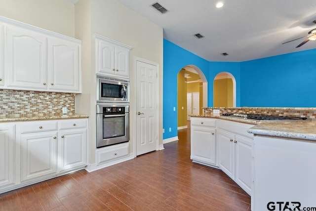 kitchen with backsplash, white cabinetry, dark hardwood / wood-style flooring, and appliances with stainless steel finishes