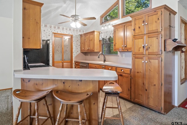 kitchen featuring a kitchen bar, sink, ceiling fan, and vaulted ceiling