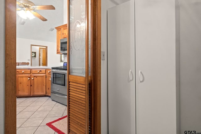 kitchen with appliances with stainless steel finishes, ceiling fan, and light tile patterned floors