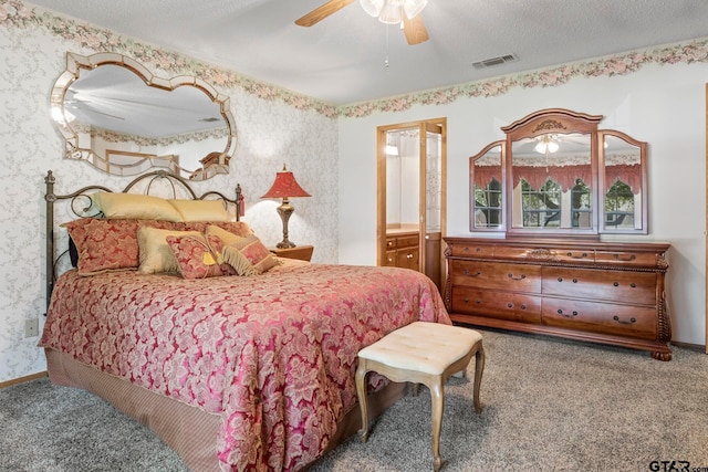 carpeted bedroom featuring a textured ceiling, ceiling fan, and ensuite bath