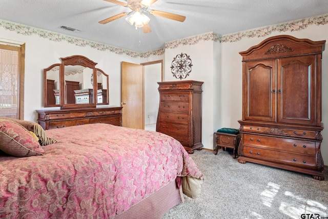 carpeted bedroom featuring ceiling fan and a textured ceiling