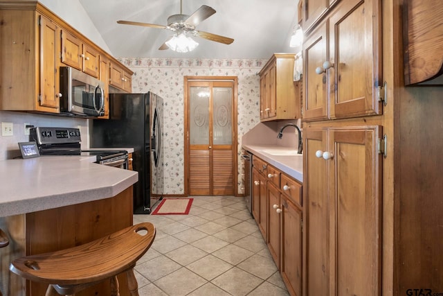 kitchen featuring stainless steel appliances, lofted ceiling, sink, light tile patterned flooring, and ceiling fan