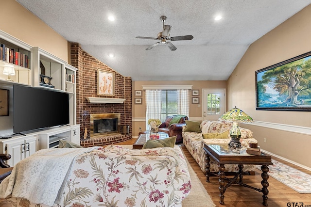 10769 Indigo Ln, Flint, TX 75762 - living room with a textured ceiling, lofted ceiling, ceiling fan, wood finished floors, and a fireplace