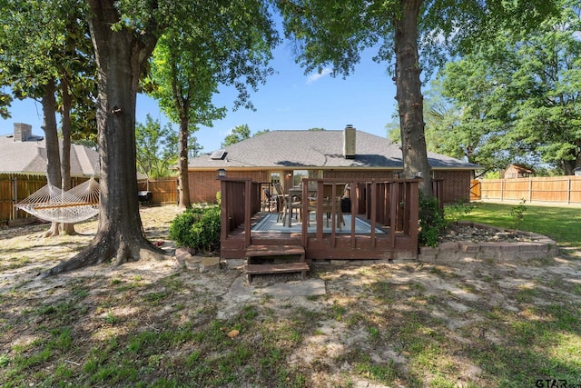 10769 Indigo Ln, Flint, TX 75762 - back of house featuring a fenced backyard, a wooden deck, brick siding, a chimney, and a shingled roof