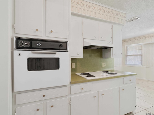 kitchen with white appliances, under cabinet range hood, a textured ceiling, and wallpapered walls