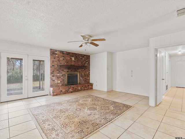 unfurnished living room with light tile patterned floors, ceiling fan, a textured ceiling, a fireplace, and french doors