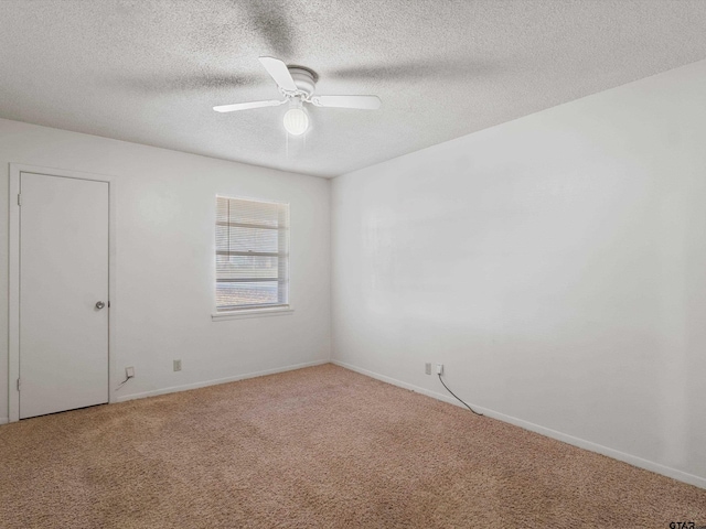 carpeted empty room featuring ceiling fan, a textured ceiling, and baseboards