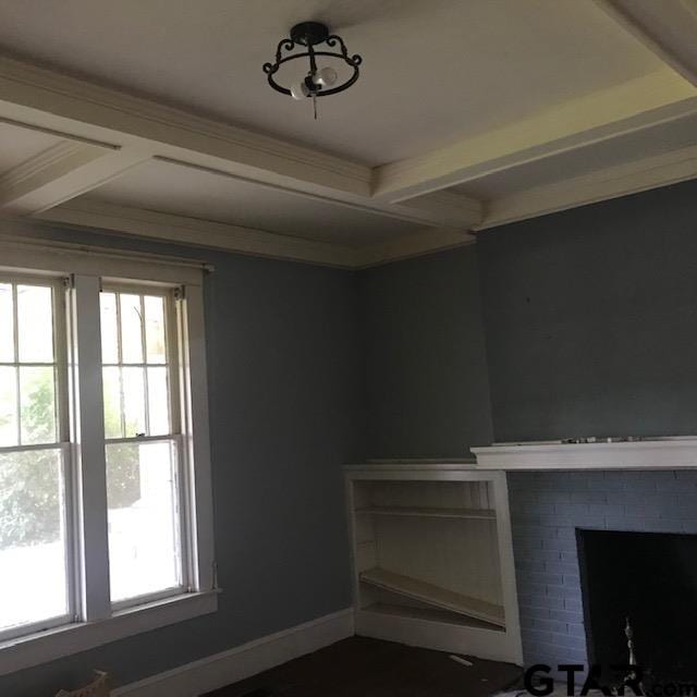 interior space with a brick fireplace, beam ceiling, and crown molding