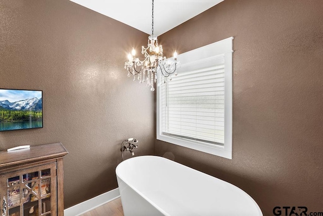 429 Coventry, Bullard, TX 75757 - bathroom with a freestanding bath, a chandelier, wood finished floors, baseboards, and a textured wall