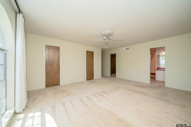 unfurnished room featuring visible vents, a ceiling fan, and light carpet