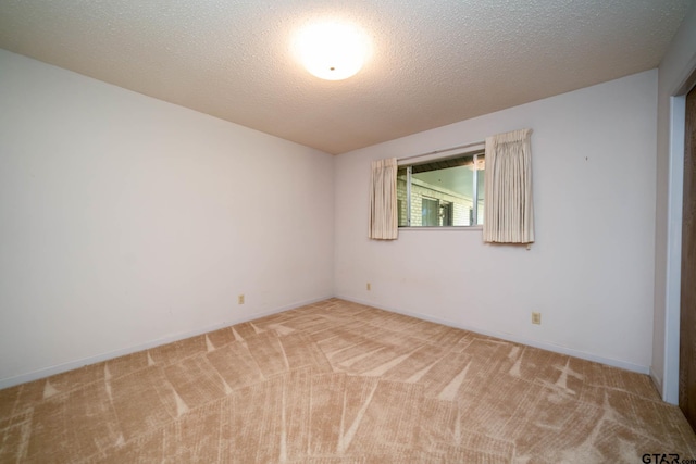 spare room featuring light carpet and baseboards