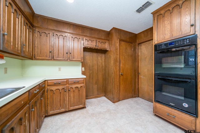 kitchen with visible vents, brown cabinets, light countertops, and dobule oven black