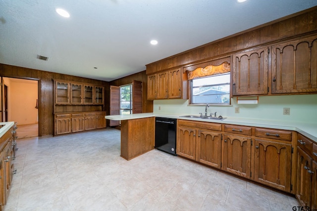 kitchen with wooden walls, dishwasher, a peninsula, and a sink