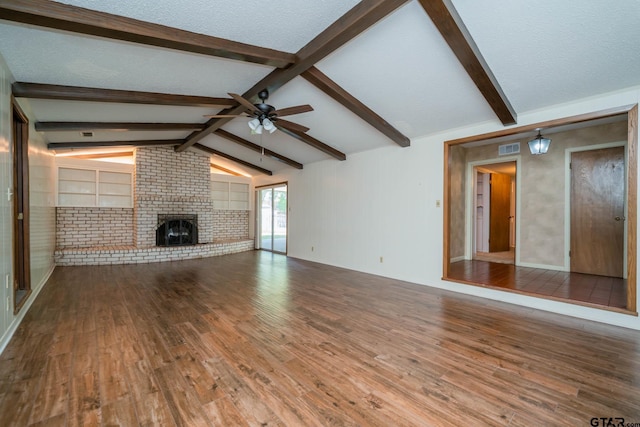 unfurnished living room featuring visible vents, lofted ceiling with beams, a brick fireplace, wood finished floors, and a ceiling fan