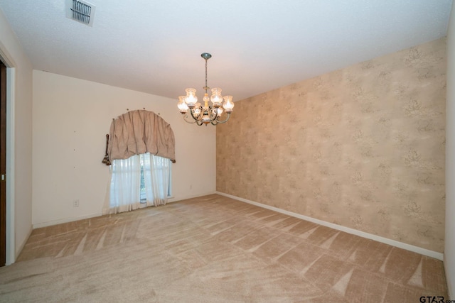 spare room with visible vents, baseboards, a notable chandelier, and carpet flooring