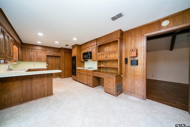 kitchen featuring open shelves, black appliances, a sink, visible vents, and a peninsula