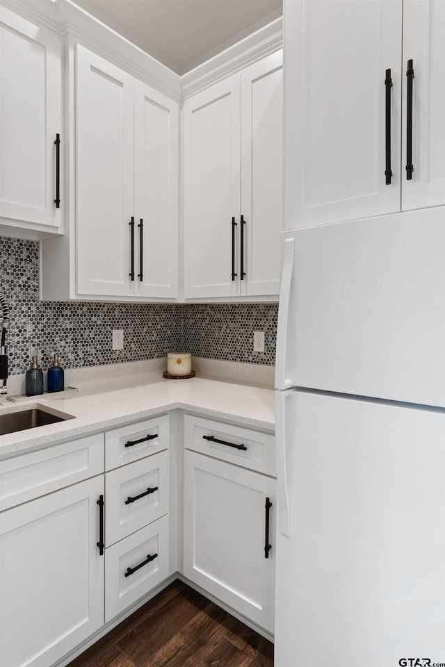 kitchen featuring dark hardwood / wood-style flooring, tasteful backsplash, sink, white refrigerator, and white cabinetry