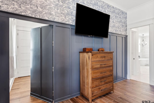 bedroom with hardwood / wood-style flooring, ensuite bathroom, a chandelier, and ornamental molding