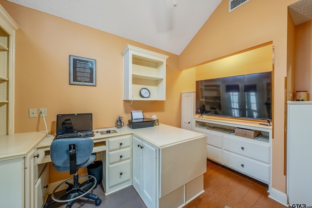 office area with built in desk, lofted ceiling, and light hardwood / wood-style floors