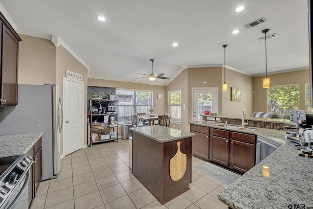 kitchen with a kitchen island, light stone countertops, sink, and appliances with stainless steel finishes