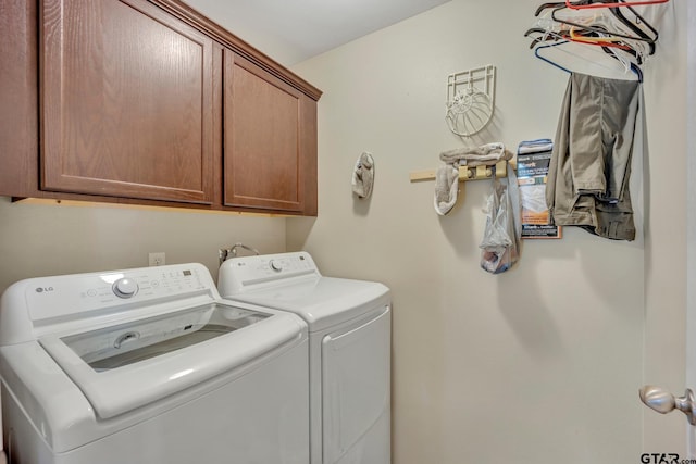 clothes washing area with washer and clothes dryer and cabinets