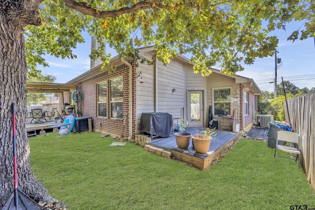 rear view of house featuring a lawn, central air condition unit, and a wooden deck