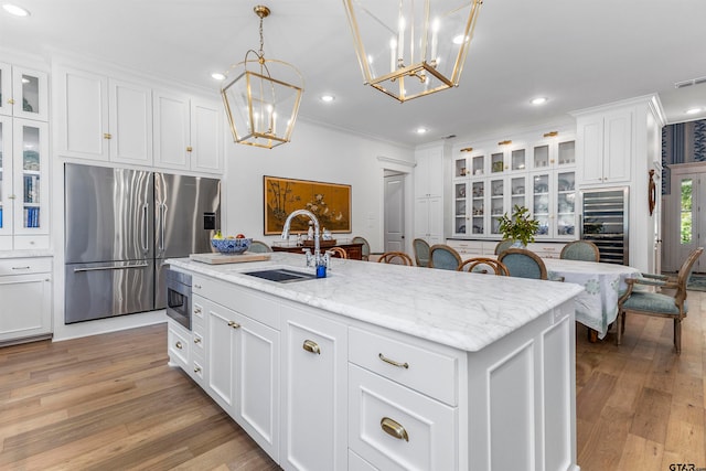 kitchen featuring a center island with sink, appliances with stainless steel finishes, sink, light hardwood / wood-style floors, and white cabinets