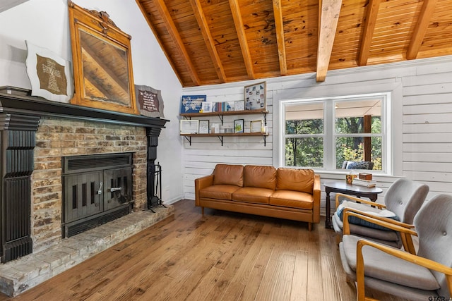 living room with vaulted ceiling with beams, wooden walls, hardwood / wood-style floors, a brick fireplace, and wooden ceiling