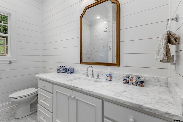 bathroom with toilet, wood walls, and vanity