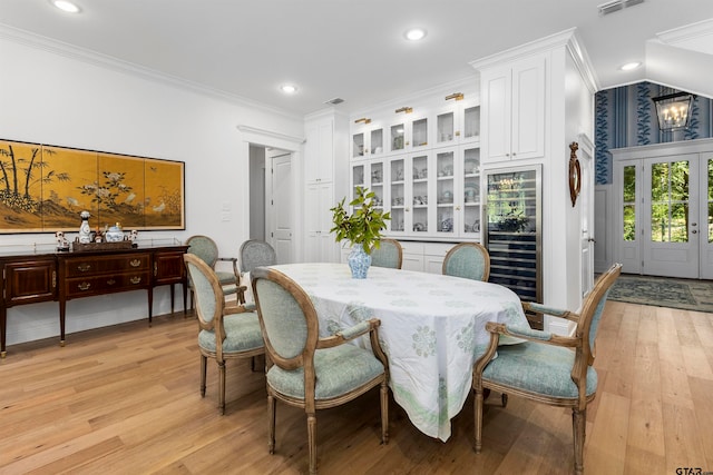 dining area featuring wine cooler, a chandelier, light hardwood / wood-style floors, and crown molding