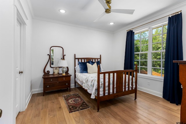 bedroom with light hardwood / wood-style floors, ceiling fan, multiple windows, and crown molding