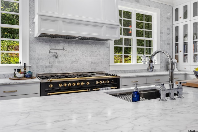 kitchen featuring backsplash, custom exhaust hood, high end range, and white cabinets