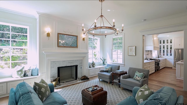 living room featuring an inviting chandelier, ornamental molding, and light hardwood / wood-style flooring