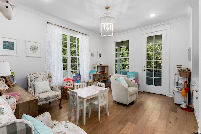 interior space featuring ornamental molding, plenty of natural light, light hardwood / wood-style floors, and a chandelier