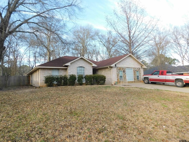 single story home featuring a front yard, concrete driveway, brick siding, and fence