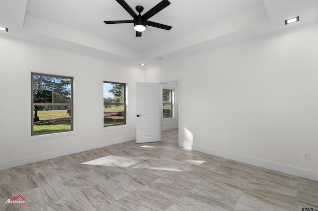 spare room with ceiling fan, ornamental molding, and a raised ceiling