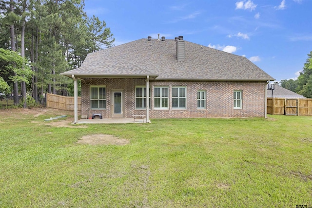 back of property featuring a fenced backyard, a chimney, brick siding, and a lawn