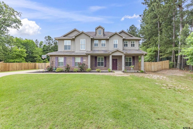 craftsman-style home featuring a porch, fence, brick siding, and a front yard
