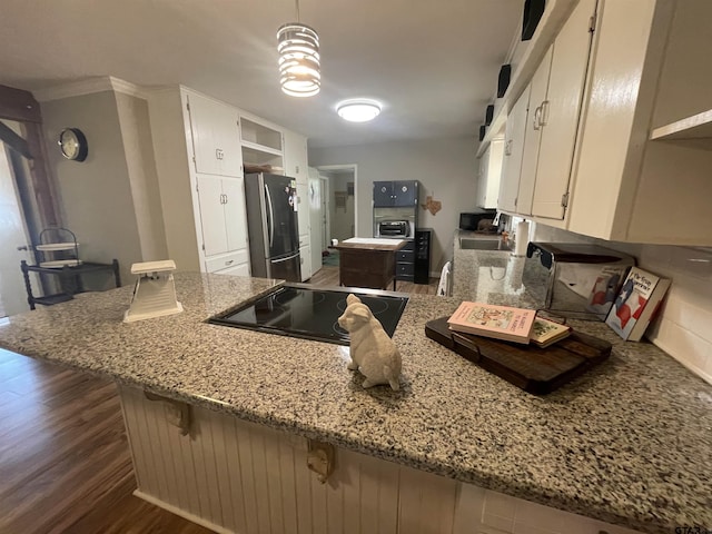 kitchen with light stone counters, white cabinets, stainless steel refrigerator, and kitchen peninsula