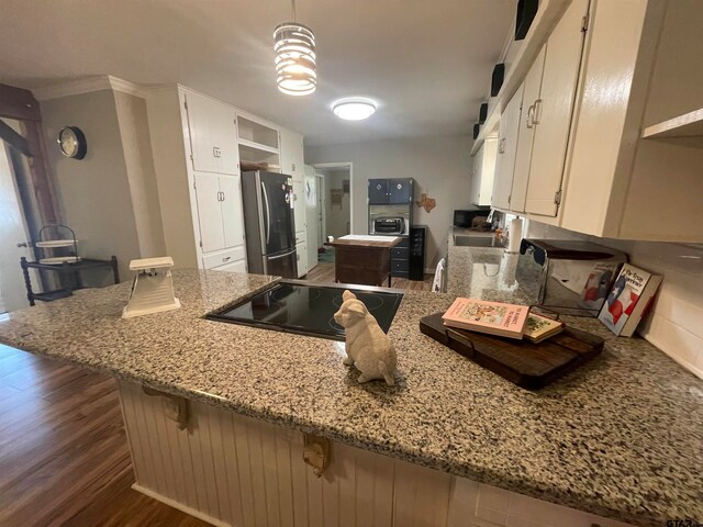 kitchen with stainless steel fridge, white cabinets, light stone counters, kitchen peninsula, and black electric cooktop