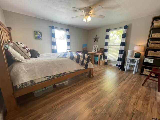 bedroom with ceiling fan, wood-type flooring, and a textured ceiling